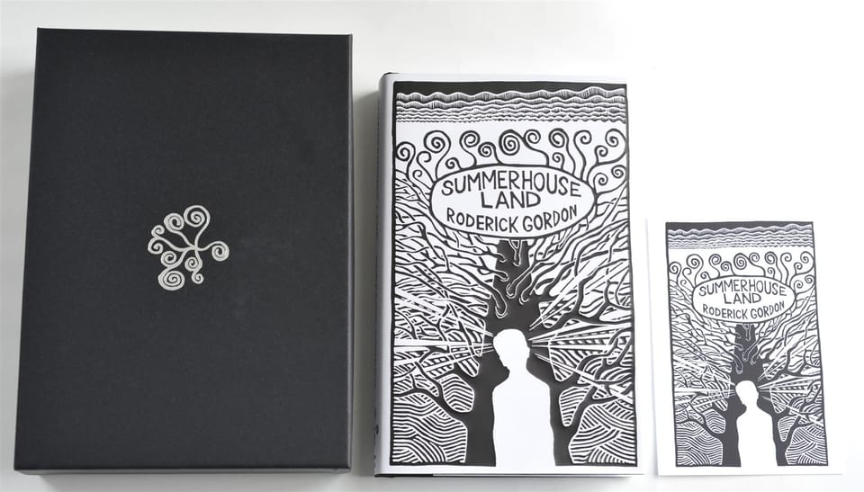 The black box embossed with a silver spiral, beside the jacketed book and a matching postcard.
